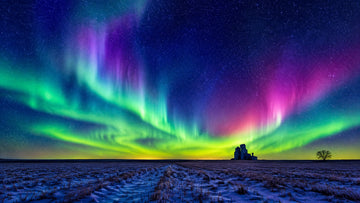 Green and magenta aurora borealis over a dark Saskatchewan prairie horizon